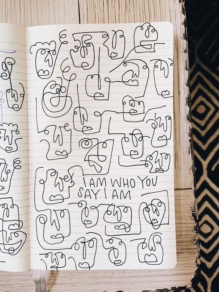 an open notebook with doodles on it sitting on a table next to a pen