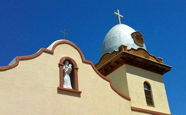 a church steeple with a statue of jesus on the top and a cross above it