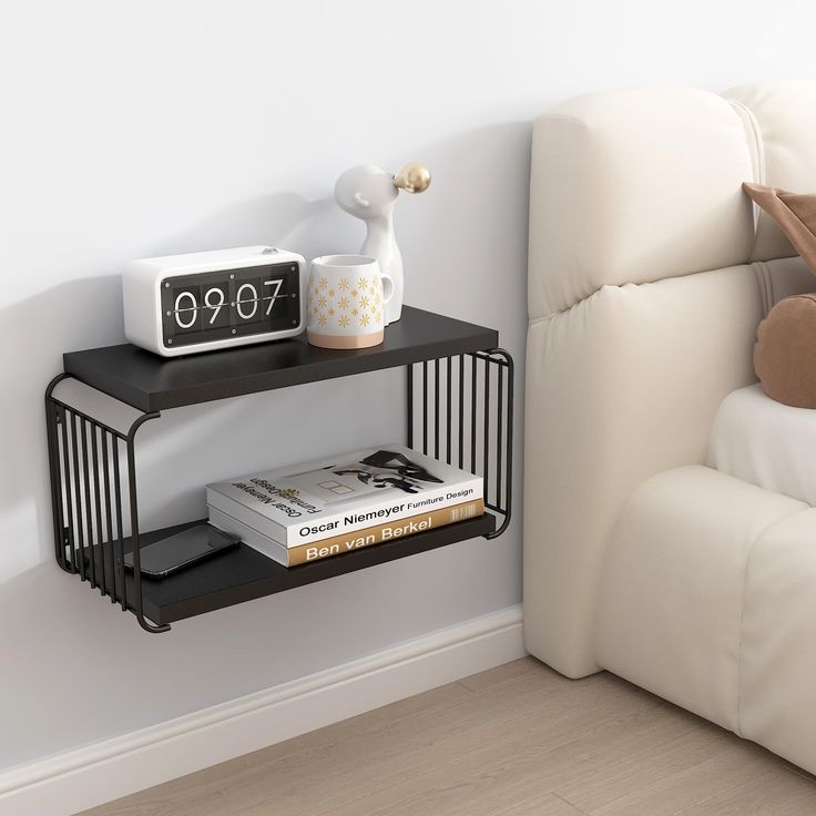 two black shelves with books and a clock on them next to a white couch in a living room