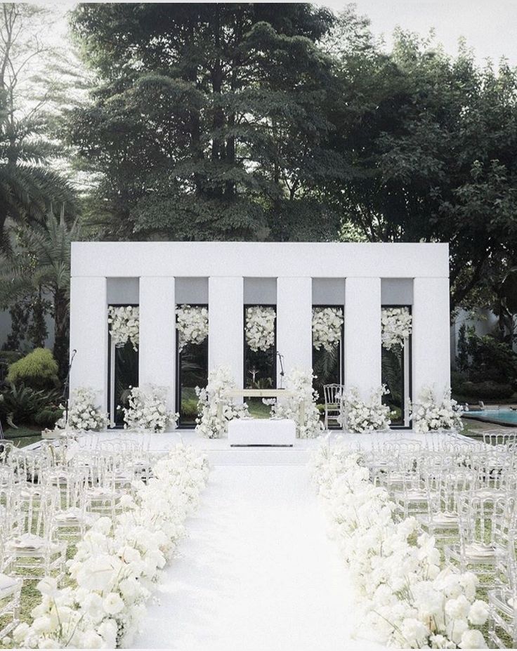 an outdoor ceremony with white flowers and chairs