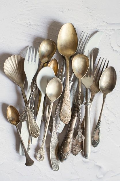 an assortment of antique silverware including spoons, forks and knives on a white surface