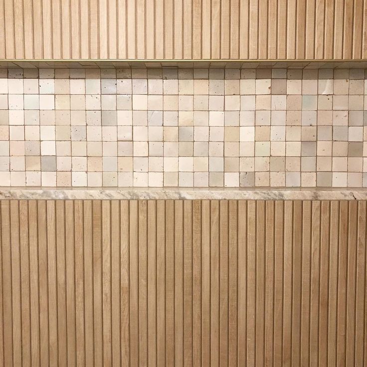 a white toilet sitting next to a wooden shower stall in a tiled bathroom with wood slats on the walls