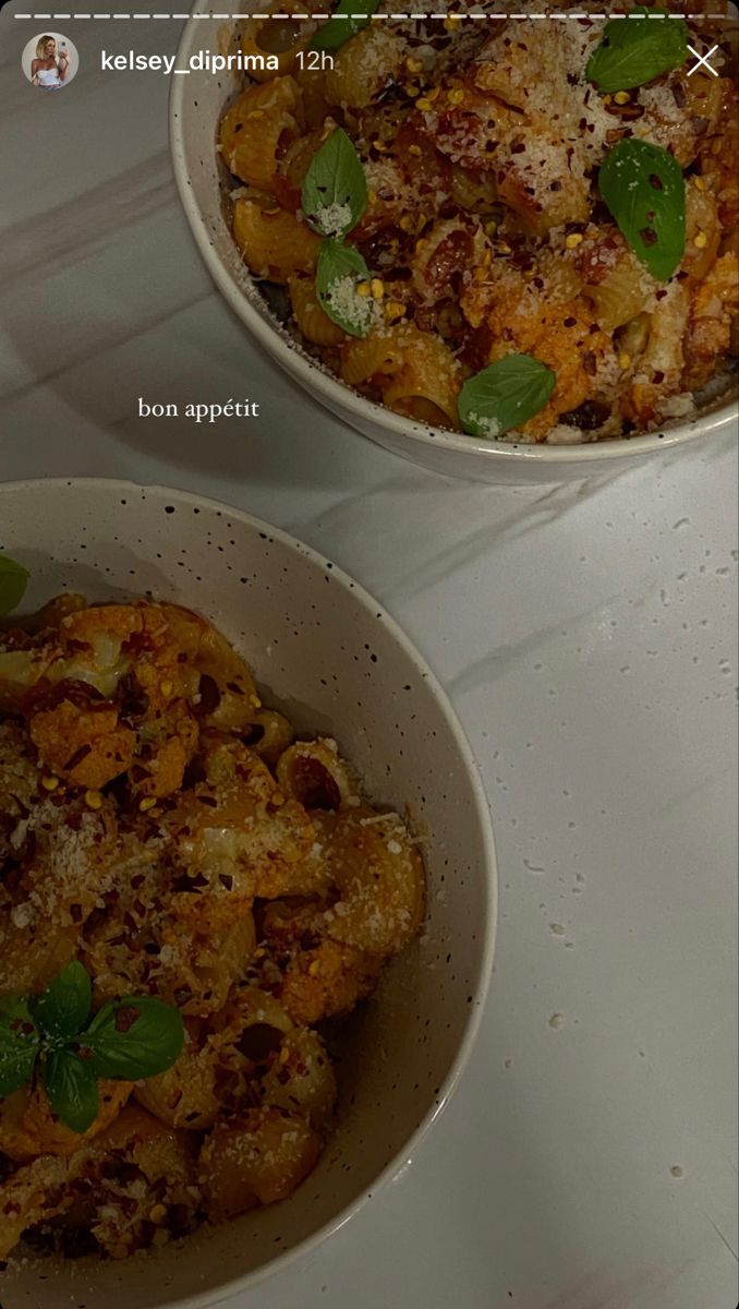 two bowls filled with food sitting on top of a white table covered in green leaves