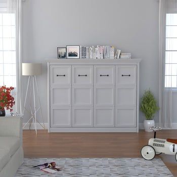 a living room filled with white furniture and lots of plants on top of the table