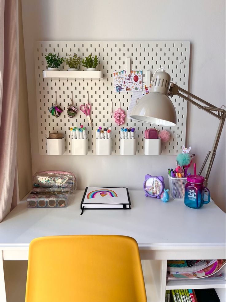 a white desk topped with a yellow chair next to a shelf filled with office supplies