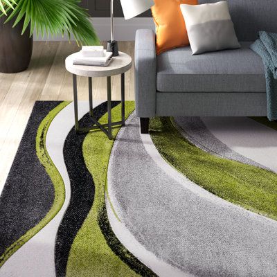 a living room with a gray couch and green rug