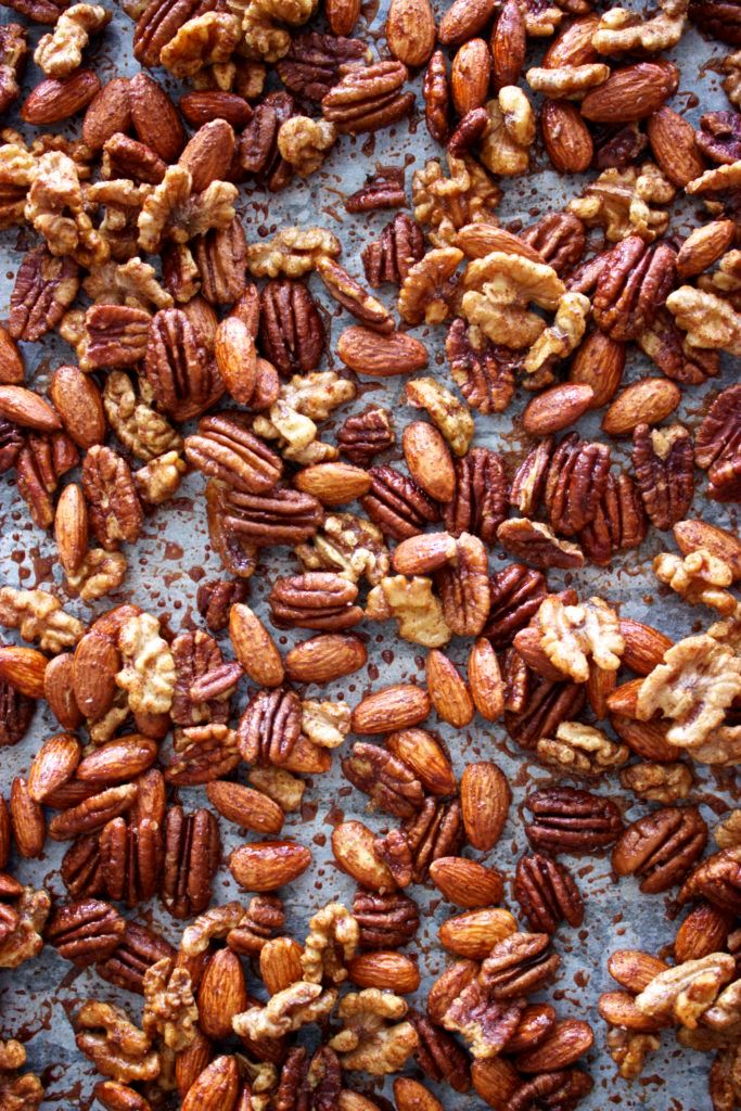 nuts are scattered on top of a sheet of tin foil, including walnuts and pecans