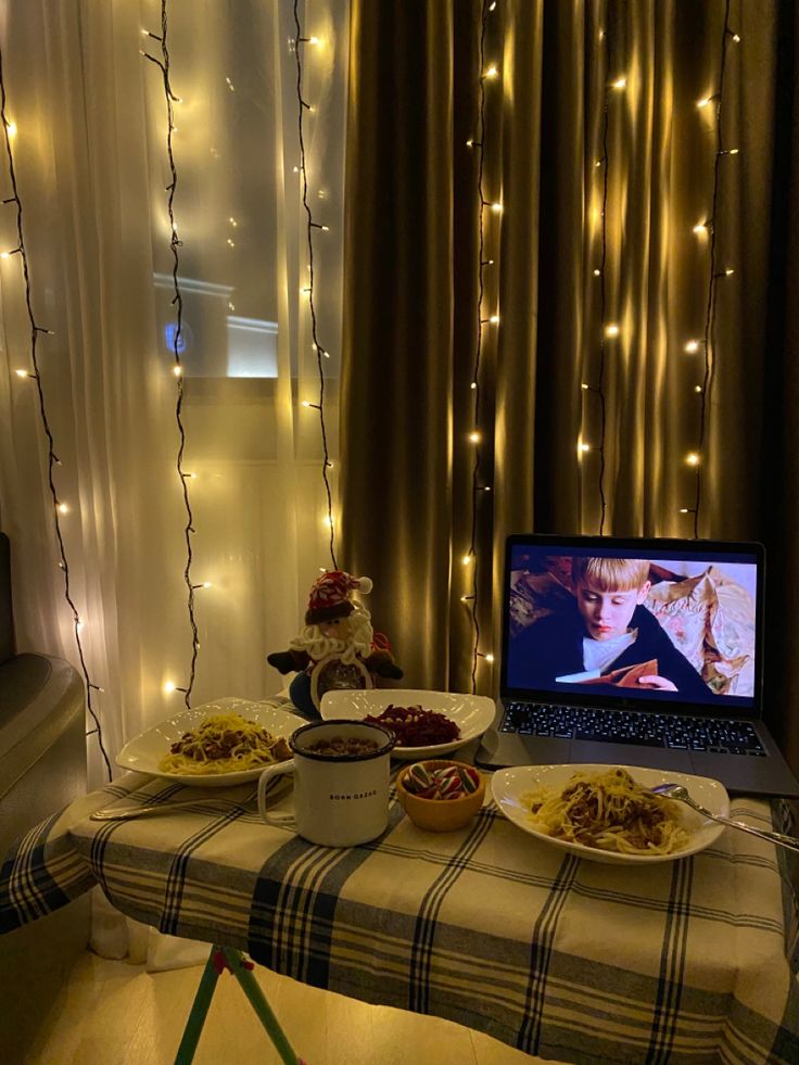 a laptop computer sitting on top of a table covered in food next to a window