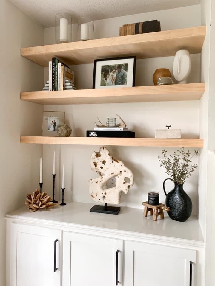 some shelves with vases, candles and pictures on top of them in a room