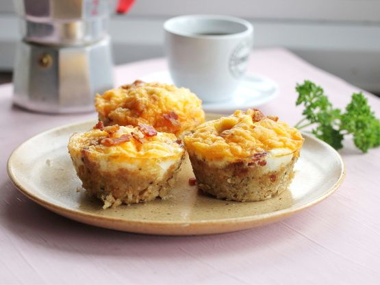 three breakfast muffins on a plate with a cup of coffee in the background