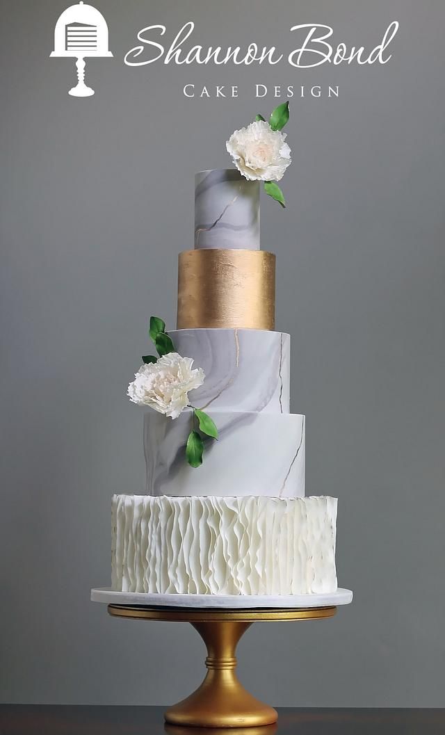 a white and gold wedding cake with flowers on top