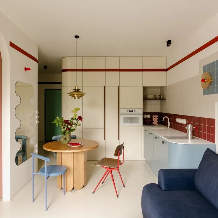 a living room and kitchen area with blue couches, chairs and a round table