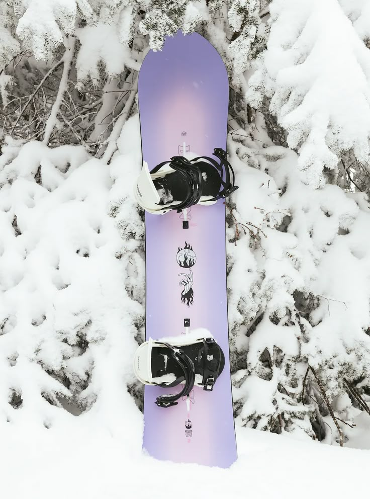 the snowboard is purple and white with black shoes on it's feet in the snow