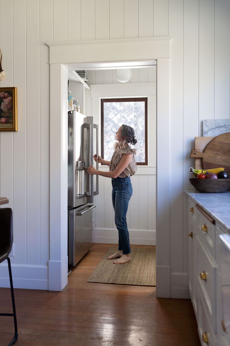 a woman is opening the refrigerator in her kitchen