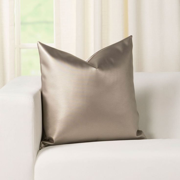 a silver pillow sitting on top of a white couch