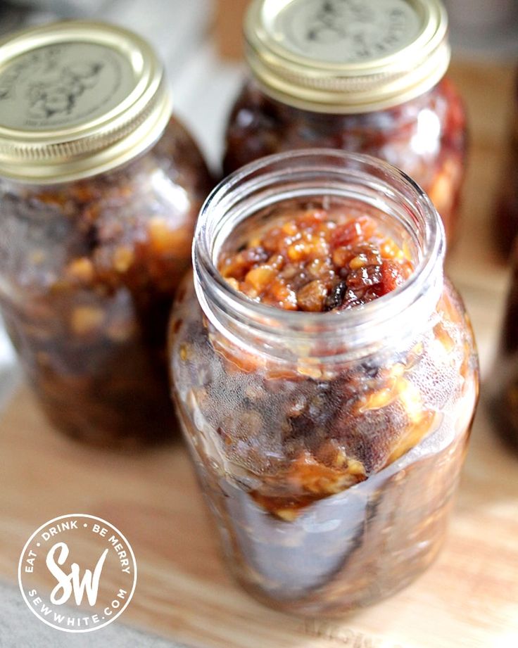 three jars filled with food sitting on top of a wooden cutting board