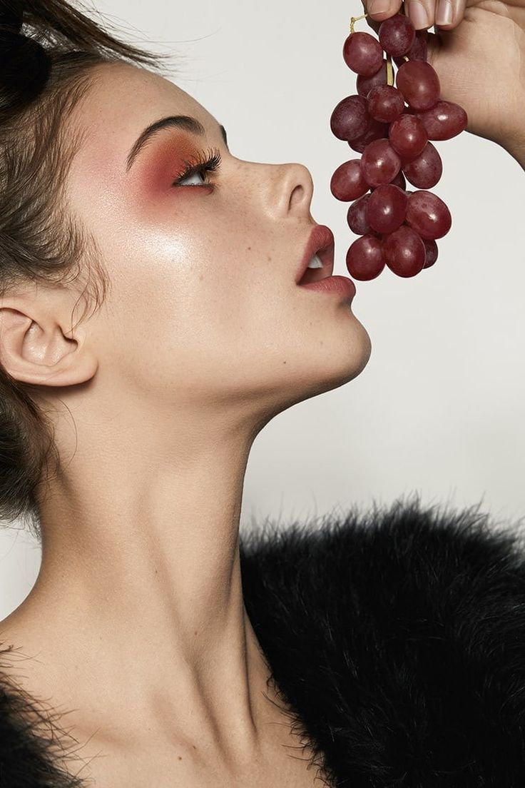 a woman holding grapes up to her face