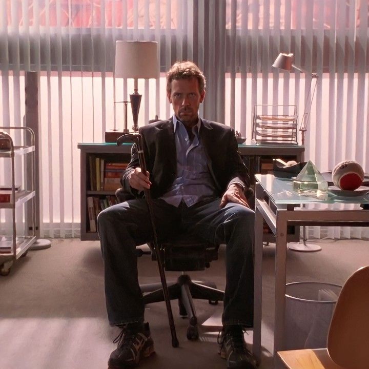 a man sitting in a chair next to a desk with a lamp on top of it