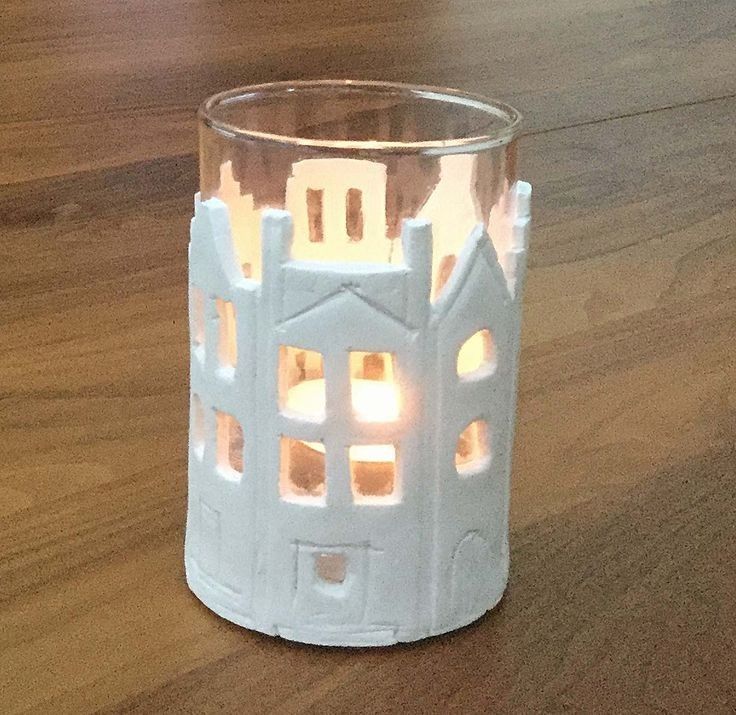 a white candle holder on a wooden table with lights in the windows and around it