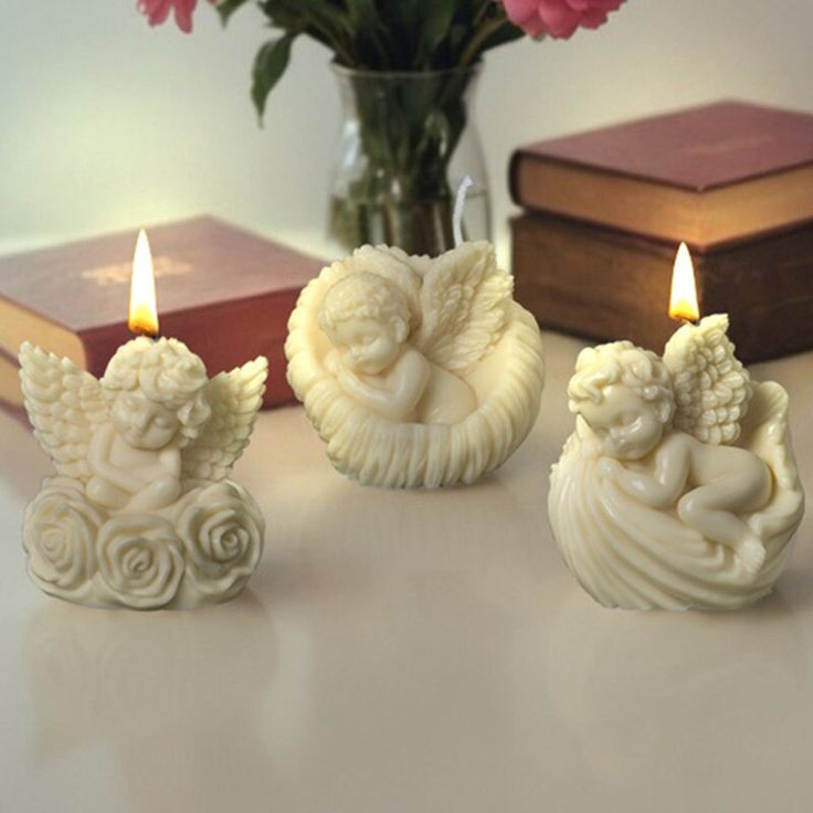 three candles are sitting on a table next to some books and pink carnations