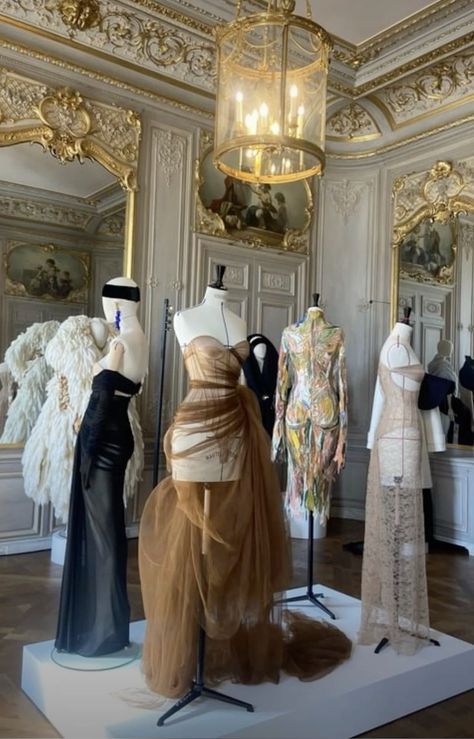 mannequins and dresses on display in an ornate room