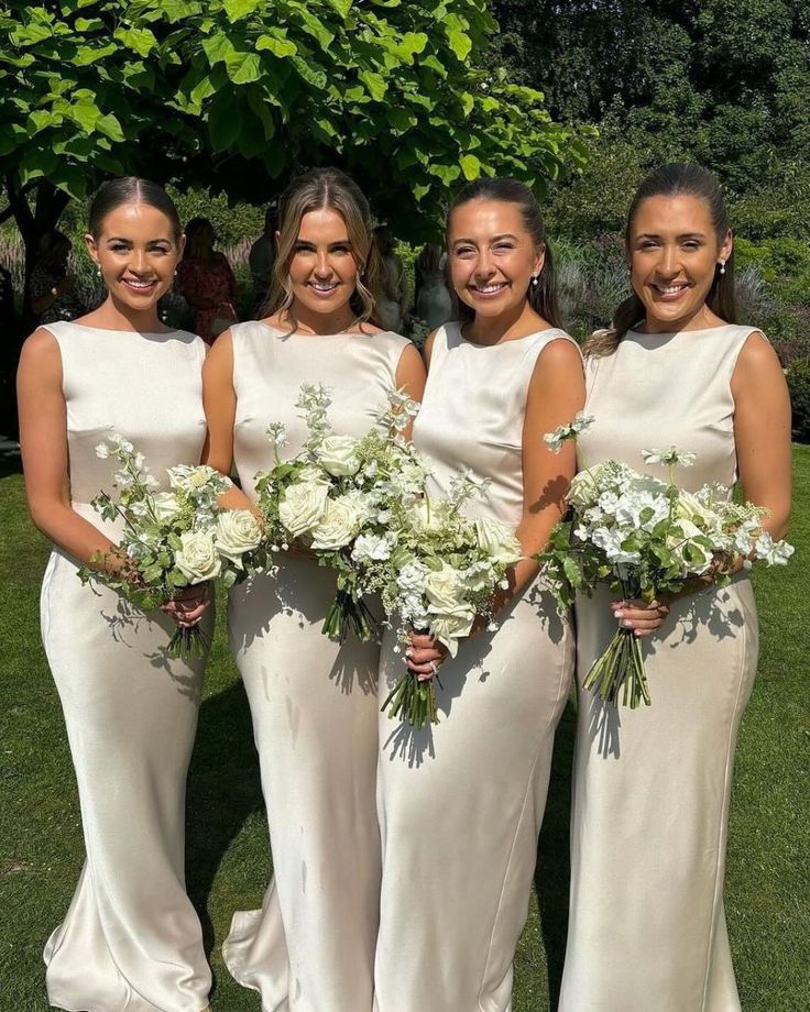 the bridesmaids are all dressed in white gowns and holding their bouquets