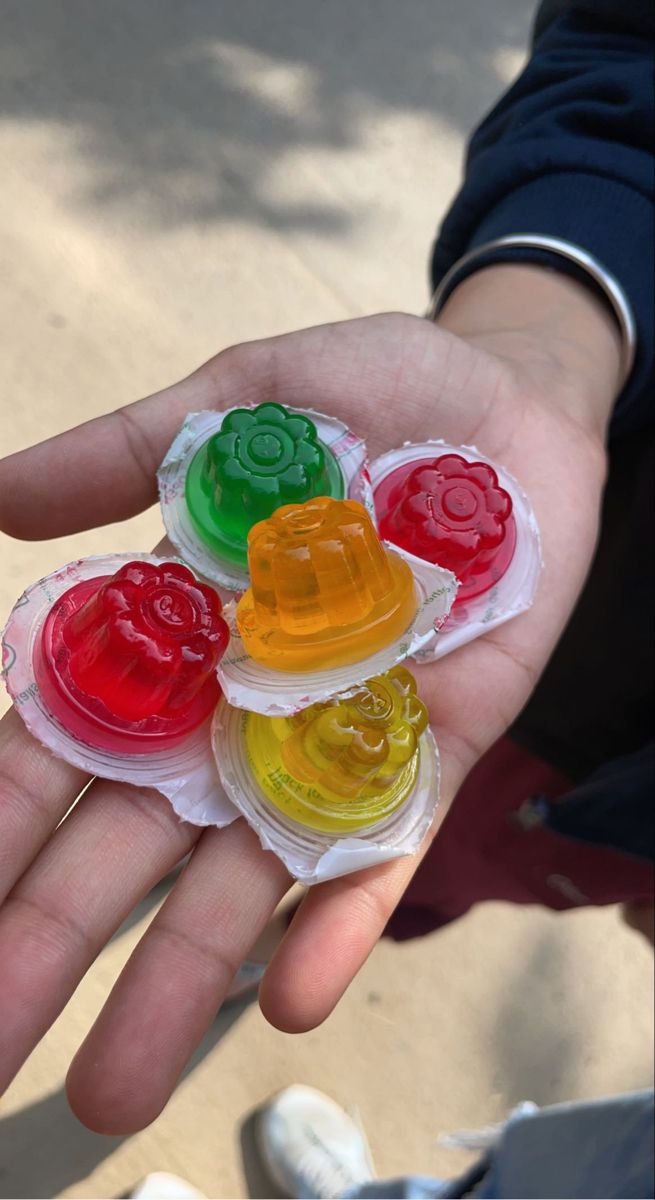 a person holding four gummy bears in their hand