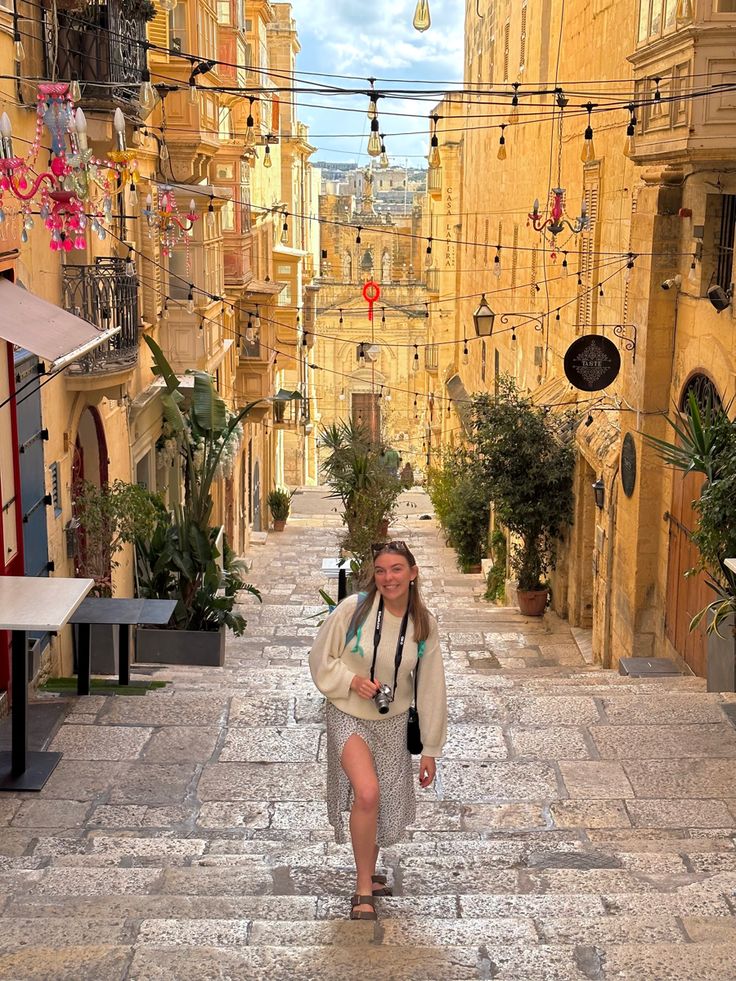 a woman is walking down the street in an alleyway with many buildings and potted plants