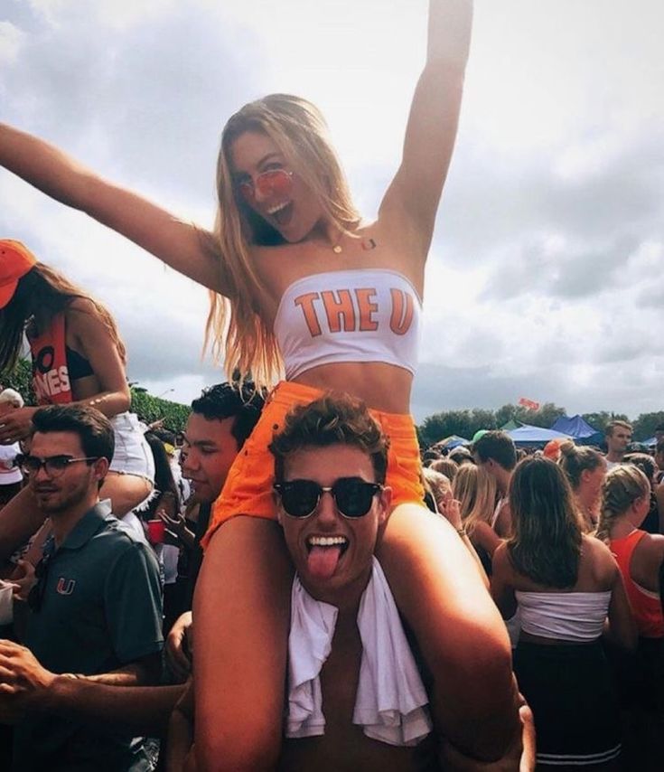 a woman is on the shoulders of a man at a music festival