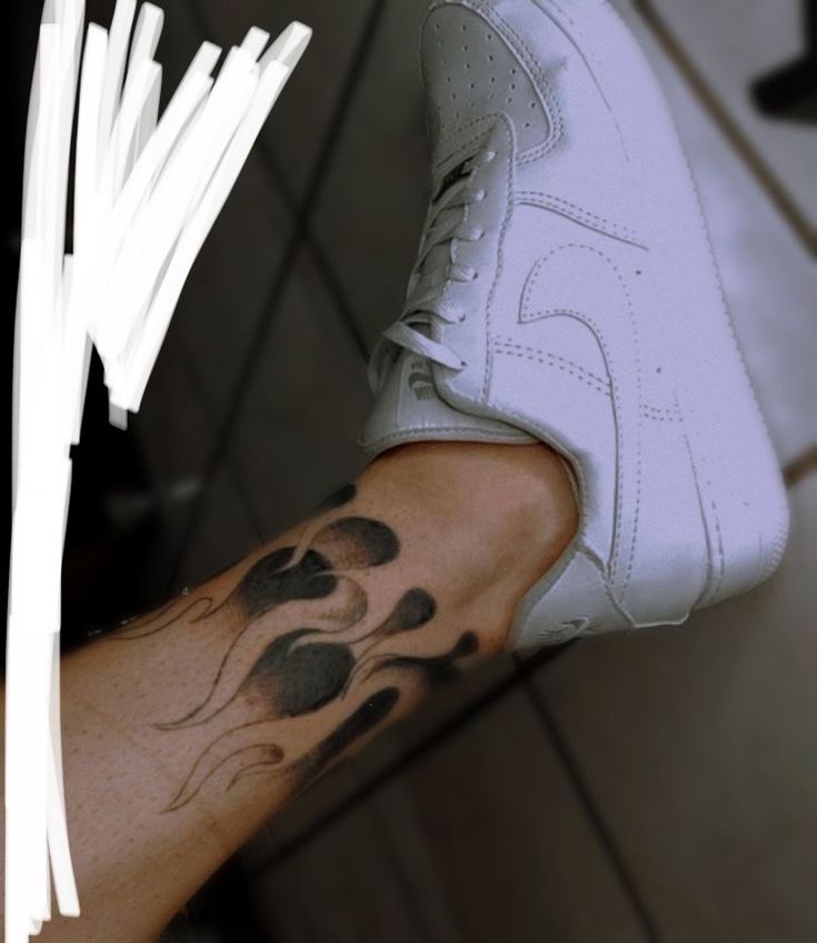 a person with a tattoo on their arm holding a tennis shoe in his left hand