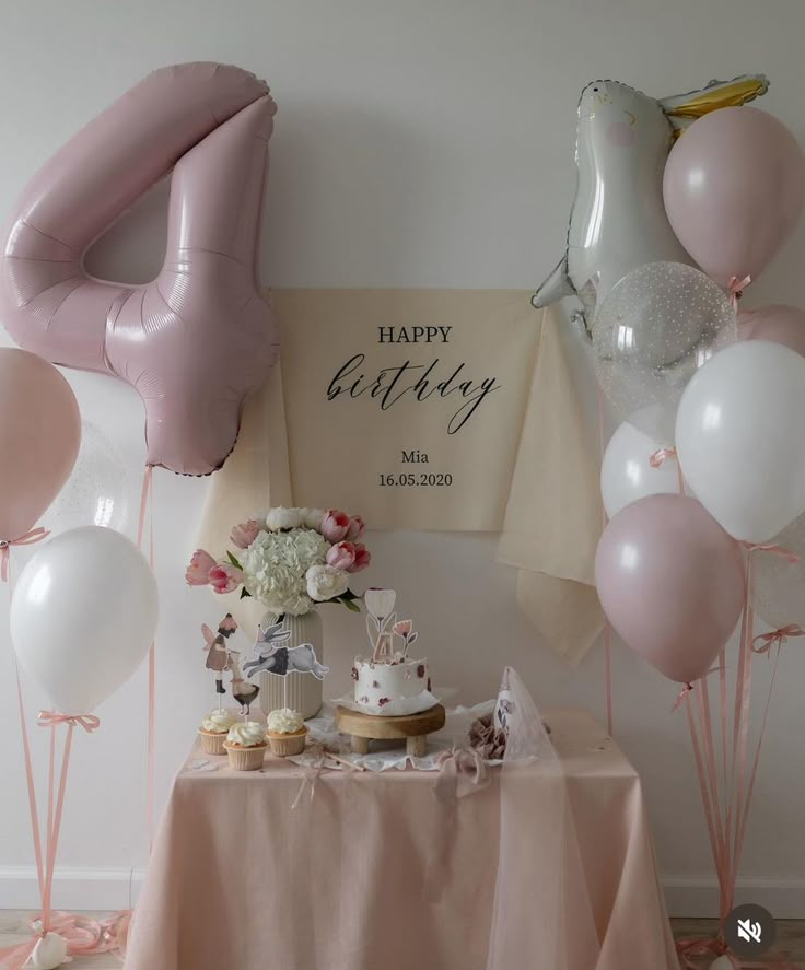 a table topped with balloons and cake next to a sign that says happy birthday on it