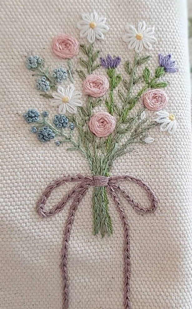 a bouquet of flowers sitting on top of a white pillow with a ribbon tied around it