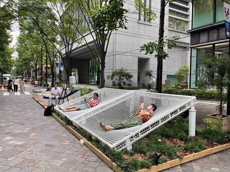 two people are laying in a large white hammock on the side of a street