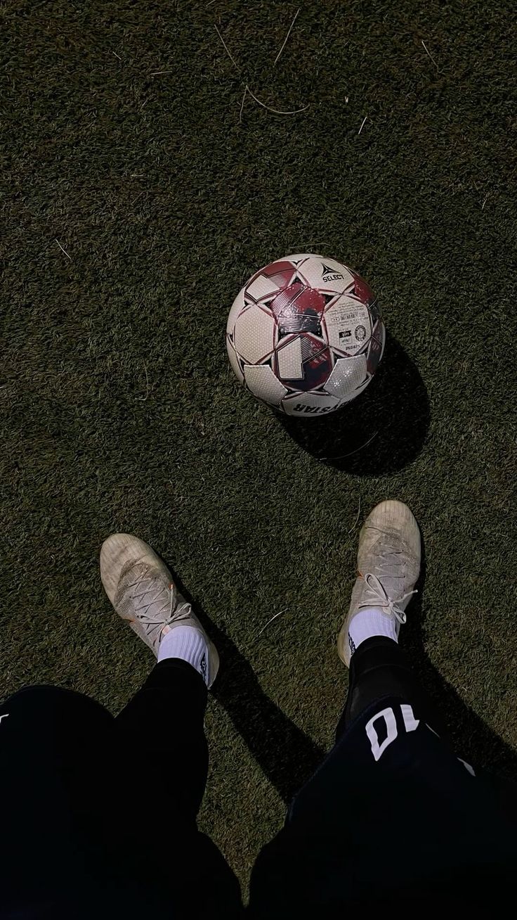 a person standing next to a soccer ball on top of a green grass covered field