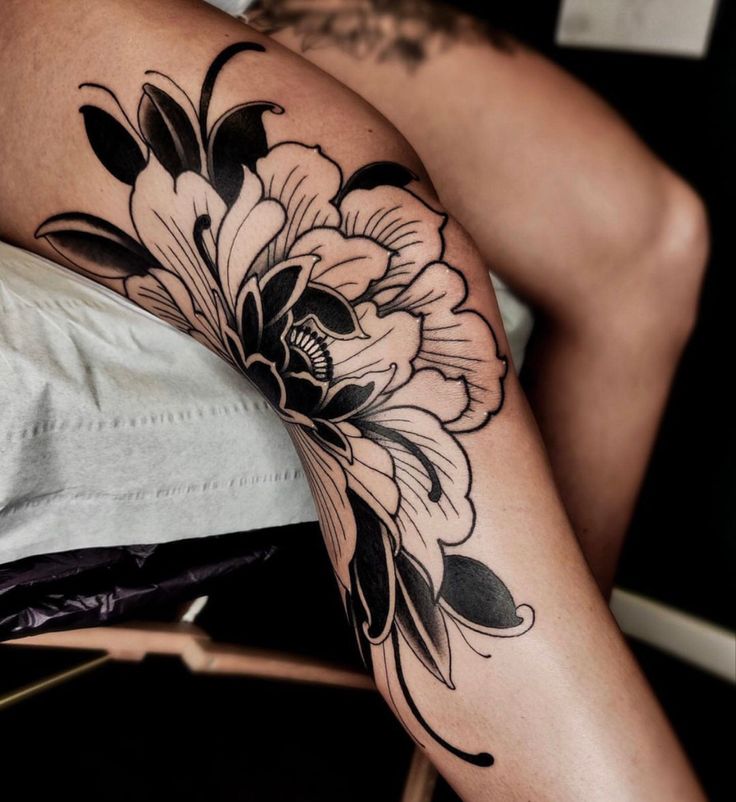 a woman's leg with a flower tattoo on the side of her thigh and an arm