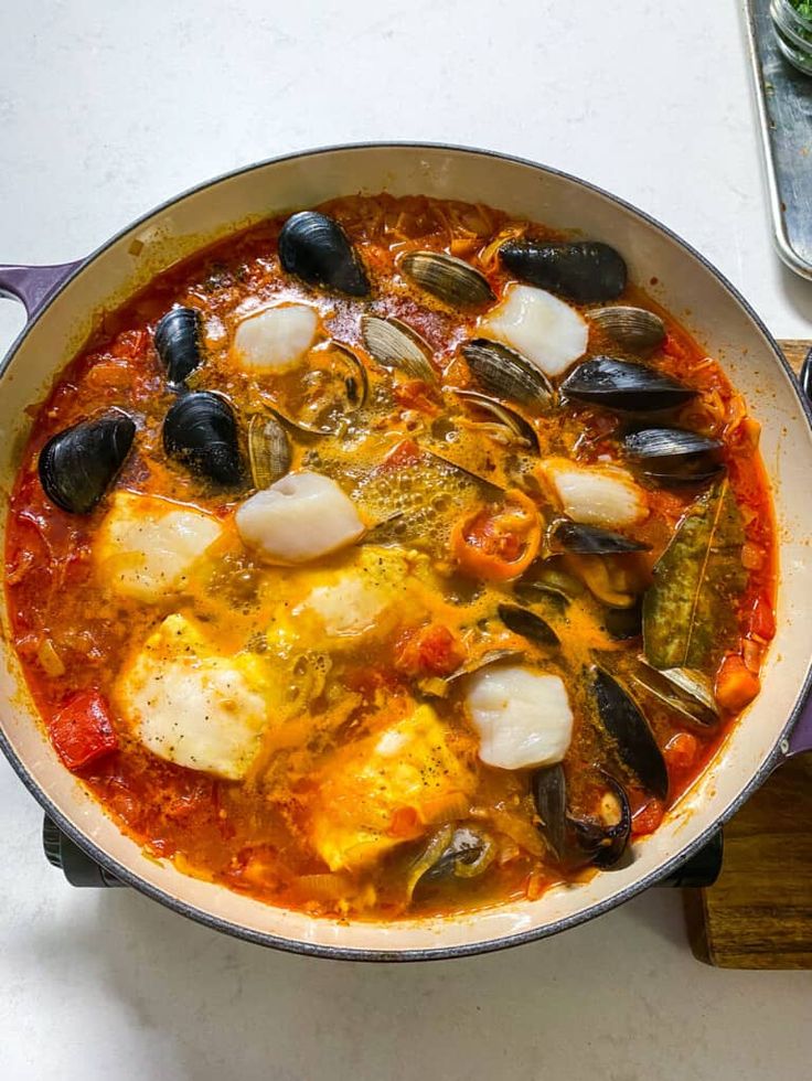 a pan filled with seafood and mussels on top of a table