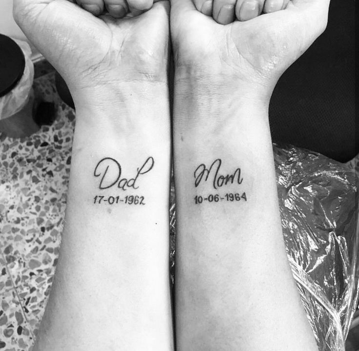 two people holding hands with tattoos on their arms that read dad and mom, in cursive writing