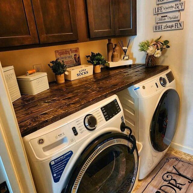 a washer and dryer in a small room with wooden cabinets on the wall