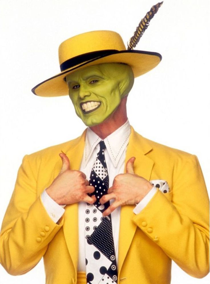 a man in a yellow suit and hat with his hands on his chest wearing a black polka dot tie