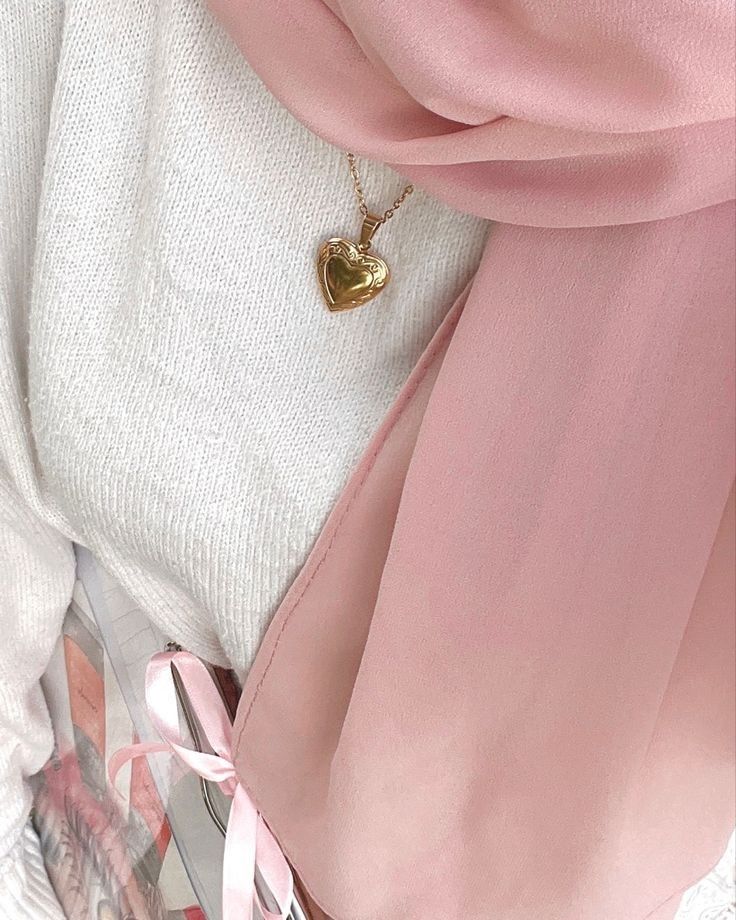 a pink scarf with a gold heart charm on it