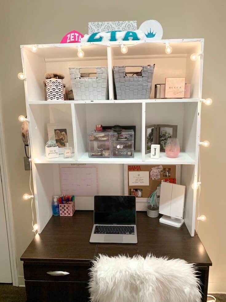 a laptop computer sitting on top of a wooden desk next to a white fur pillow