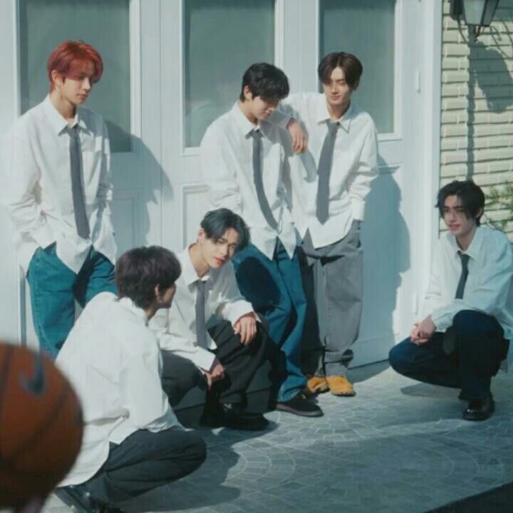 group of young men sitting on the ground in front of a building with basketballs