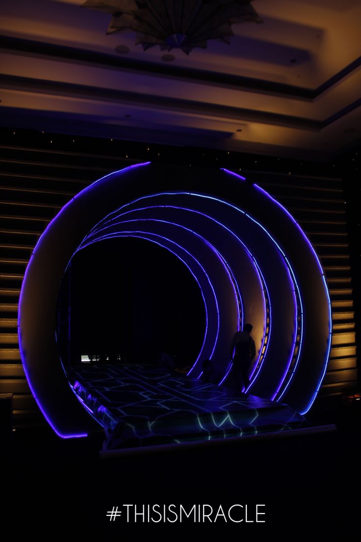 a person standing in front of a large circular object with blue lights on the ceiling