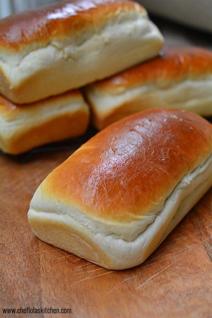 three bread rolls sitting on top of a wooden cutting board next to eachother