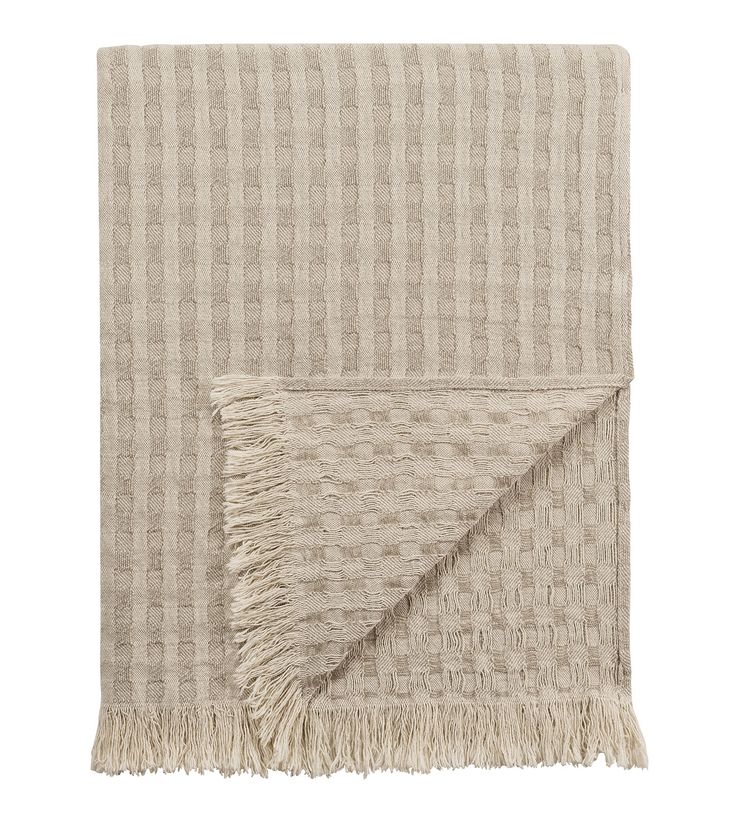 the beige and white checkered blanket with fringes is folded on top of it