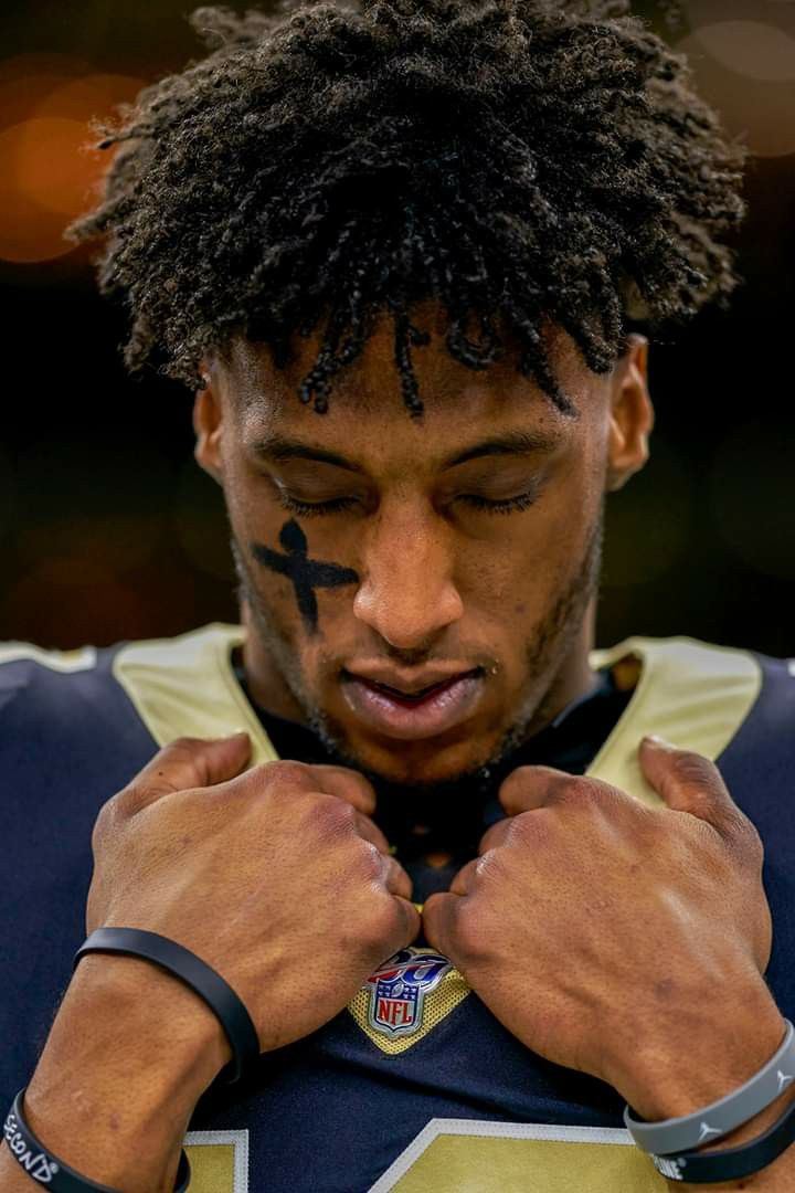 a close up of a person wearing a jersey and holding his hands on his chest