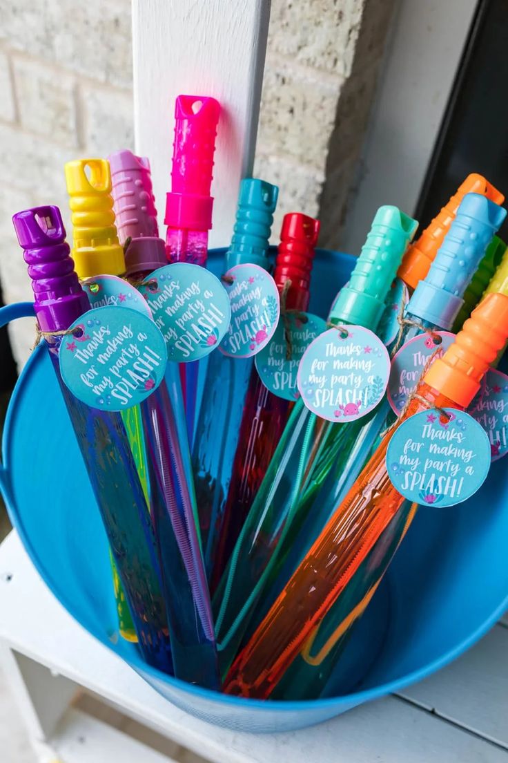 a bucket filled with lots of different colored straws and paper tags on top of them