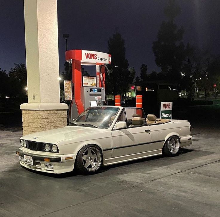 a white car parked in front of a gas station