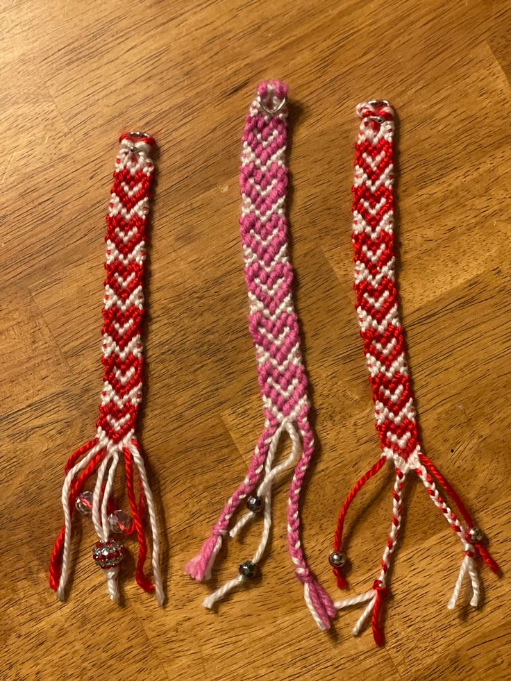 two pink and white braided ties sitting on top of a wooden table next to each other