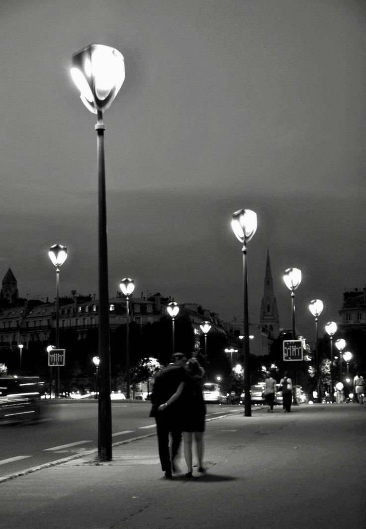 black and white photograph of two people standing under street lights